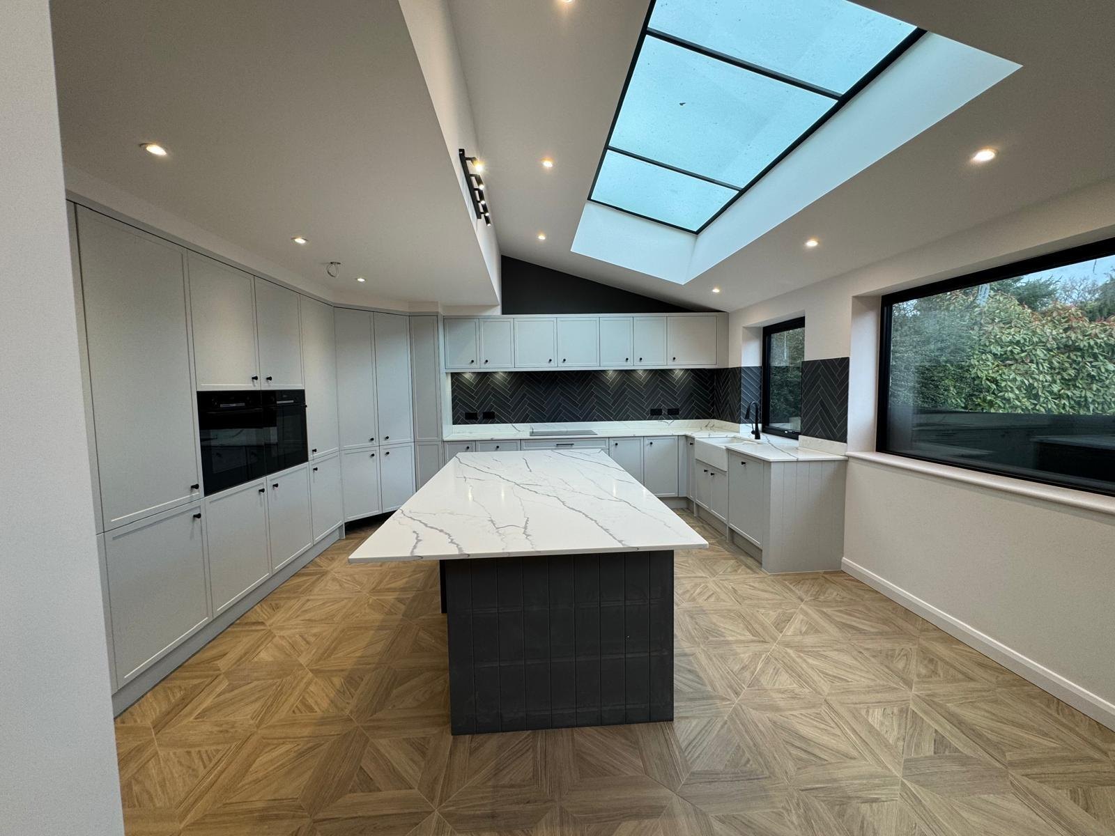 A bright kitchen extension with a large skylight and marble worktops