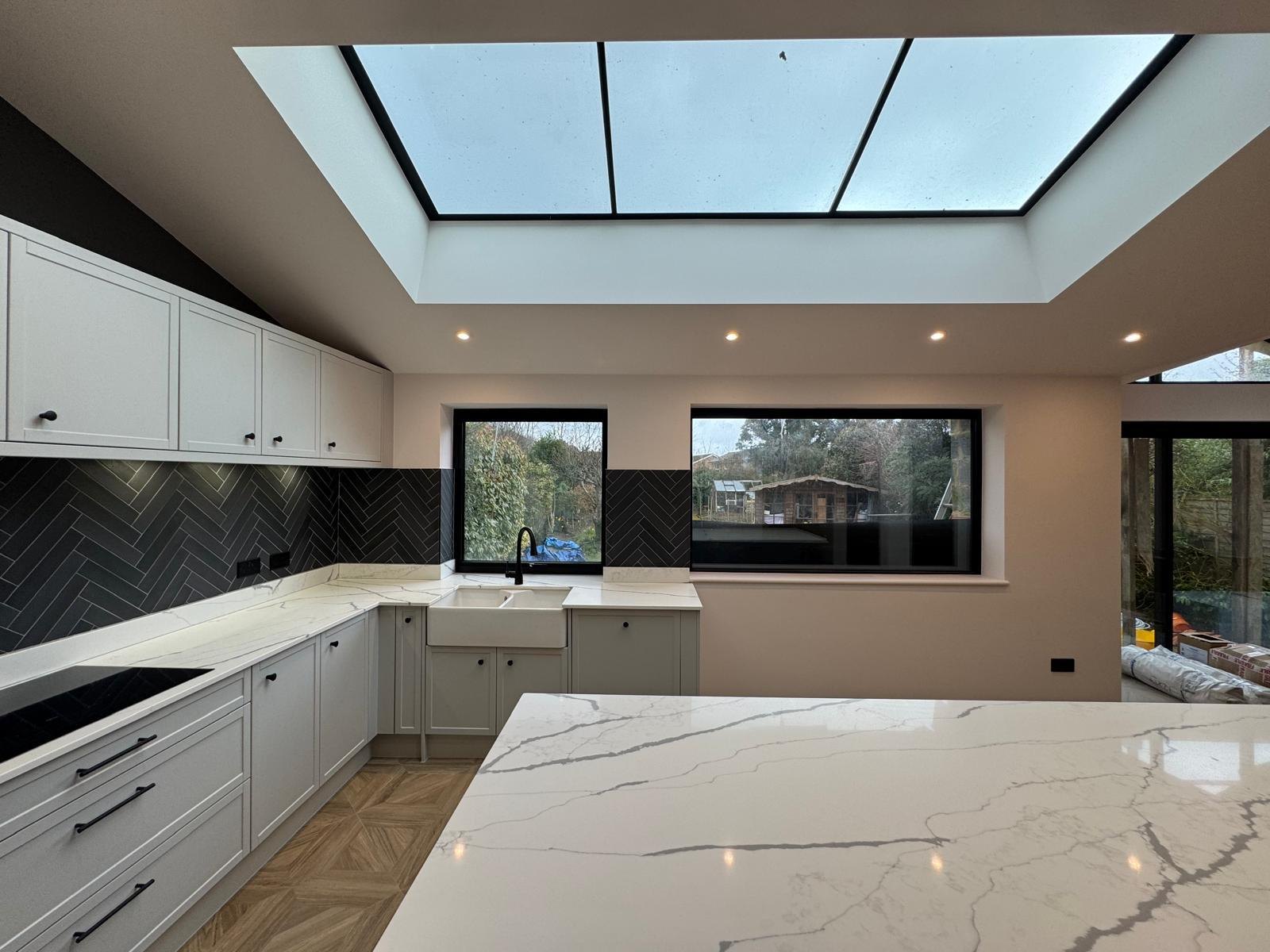 A finished open-plan kitchen with a large marble island, fitted by Professional Polish Builders