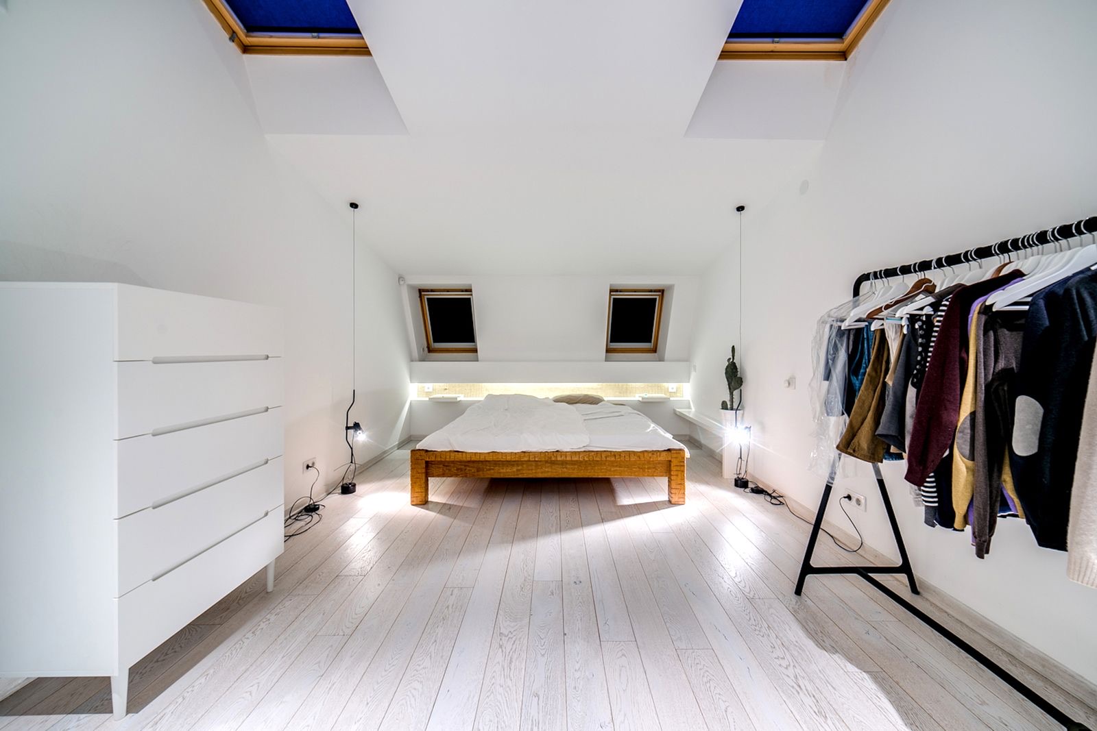 A clean, modern white loft conversion bedroom with rooflights